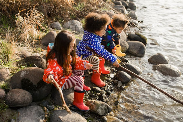 Tre bambini giocano in riva al fiume