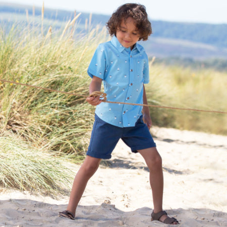 un bambino che gioca in mezzo alla natura con indosso una camcia azzurra