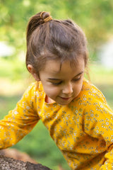 Bambina indossa maglietta a maniche lunghe gialla con fiorellini bianchi