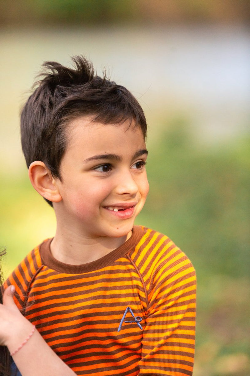 Bambino sorridente con maglietta a maniche lunghe a righe arancione