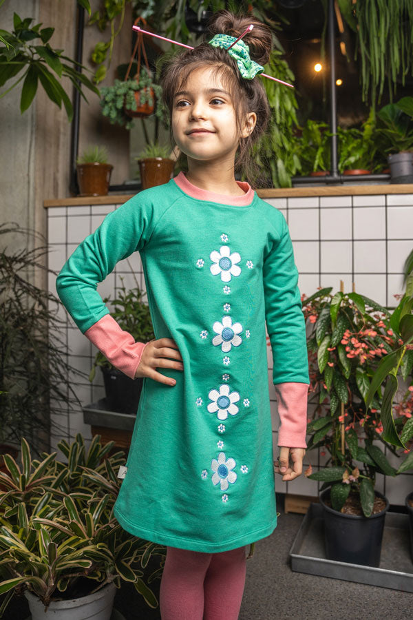 bambina indossa abito verde smeraldo con girocollo bordato e polsini a contrasto rosa antico