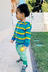 Bambino indossa felpa a righe blu, gialla e pantaloni verde acqua