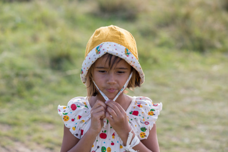 bambina indossa cappellino reversibile giallo e panna