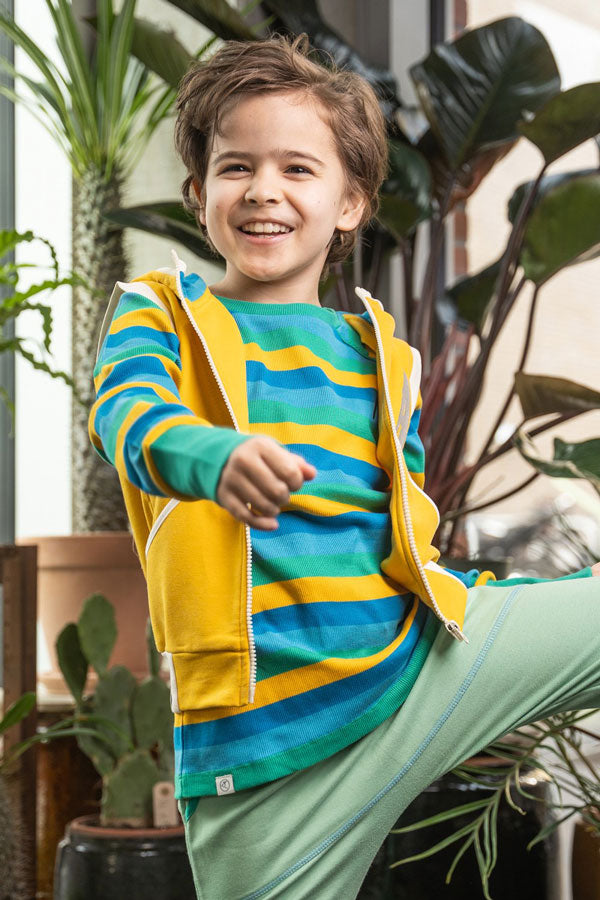 bambino indossa felpa colorata, gilet giallo e pantaloni verde acqua