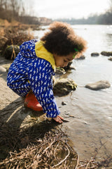 Bambino gioca con l'acqua indossa giacca impermeabile azzurra con fulmini