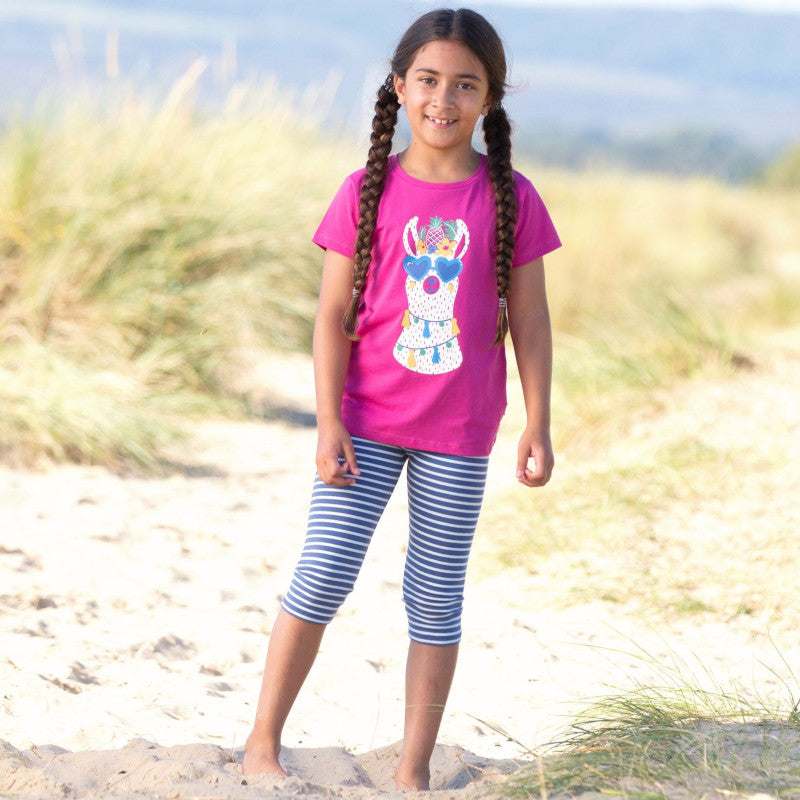 bambina gioca in spiaggia indossa maglietta rosa con stampa colorata e leggings a righe bianchi e blu