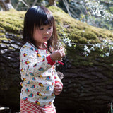 bambina indossa maglietta a maniche lunga con pettirossi colorati e pantaloni a righe bianchi e rossi